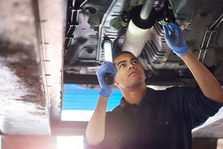 Mechanic inspects a vehicle on a ramp with a torch