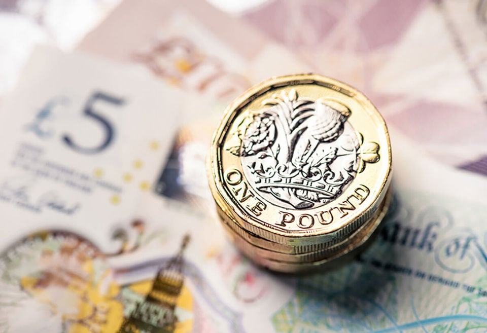 Pile of pound coins on top of £5, £10 and £20 notes