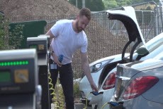 Man in white T-shirt plugging a car in at an EV charge point
