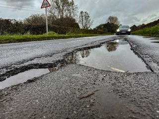 Car driving towards pot-holes filled with water