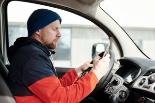 Man looking at mobile sitting in van