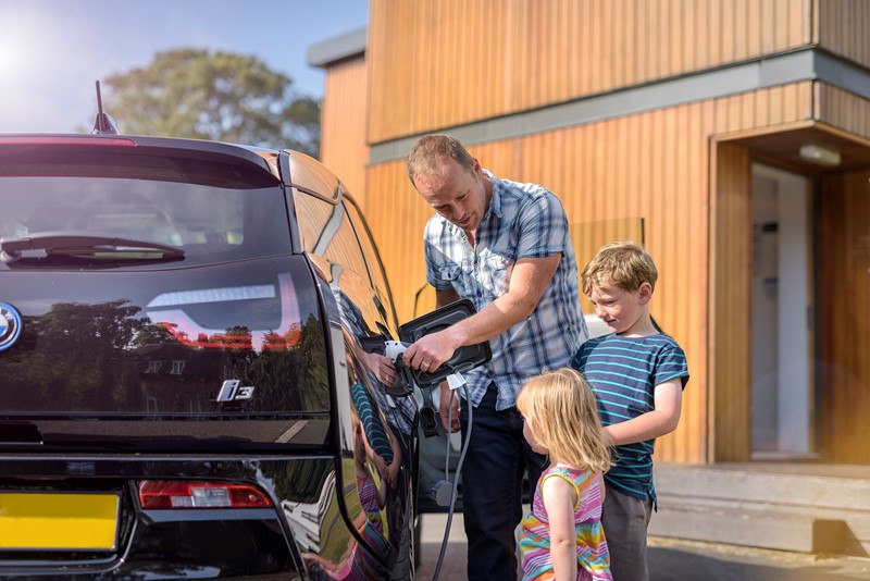 Man and his two children using EV charge point