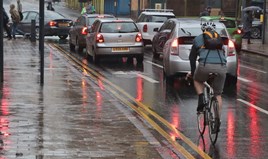 Traffic at a red traffic light on a rainy day with a cyclist in the foreground