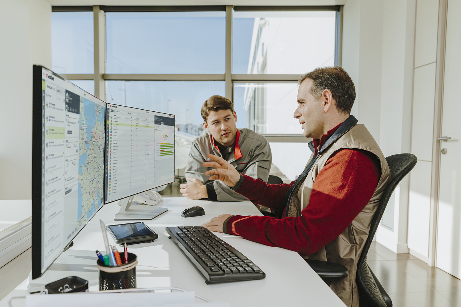 Man discussing something on his computer at his desk with a colleague 