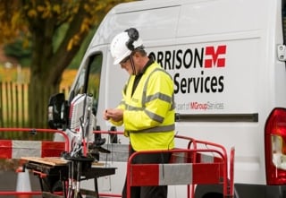 Engineer in hard hat with M Group van in background