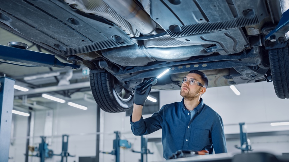 Mechanic examining the underside of a vehicle