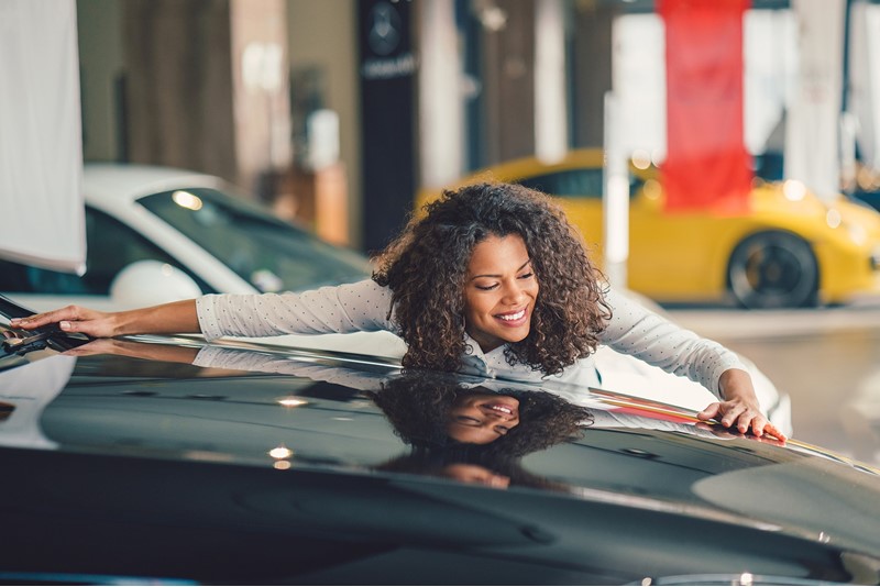 Smiling woman lies against the bonnet of a car