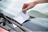 Parking ticket being placed on car windscreen