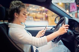 Mobile looking at her mobile phone while driving