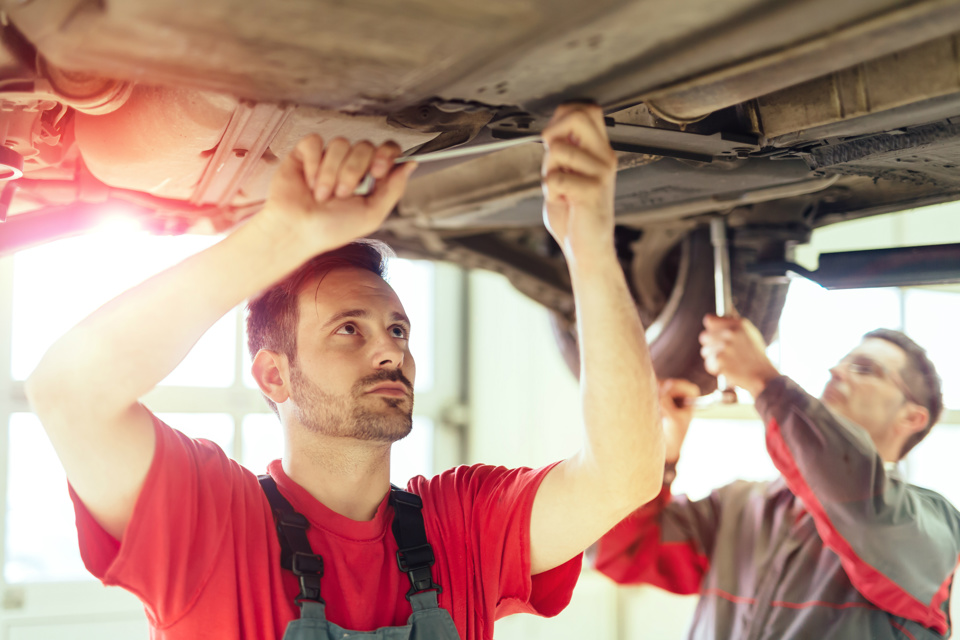 Two mechanics working on a car