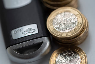 Vehicle key and pile of pound coins